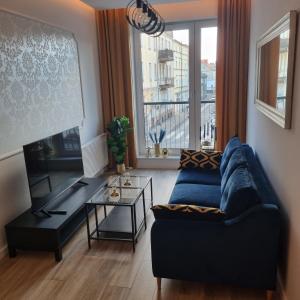 salon z niebieską kanapą i stołem w obiekcie Apartament Skarbowa w mieście Leszno