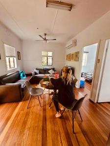 a woman sitting at a table in a living room at Ella May Holiday Flats in Tuross Heads