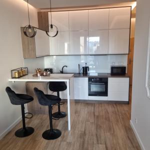 a kitchen with white cabinets and black stools at Apartament Skarbowa in Leszno