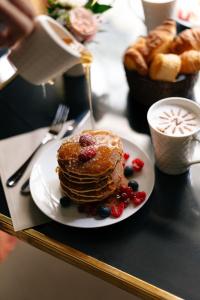 a plate of pancakes with berries and a cup of coffee at Hôtel Napoleon Paris in Paris