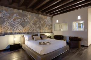ein Schlafzimmer mit einem Bett und einem Wandbild von Giraffen in der Unterkunft PALAZZO DUOMO Suites in Udine Center in Udine