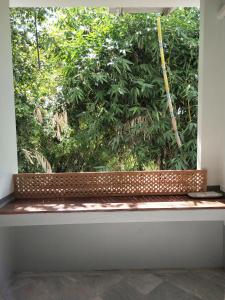 - une fenêtre dans une chambre avec un grand arbre dans l'établissement Reun Sroyraya Boutique Home เรือนสร้อยระย้าบูทิค, à Ban Kok Sai