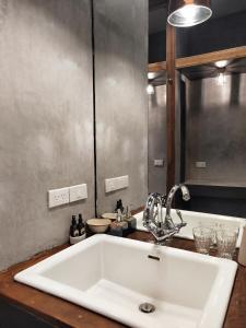 een badkamer met een witte wastafel en een spiegel bij Reun Sroyraya Boutique Home เรือนสร้อยระย้าบูทิค in Ban Kok Sai