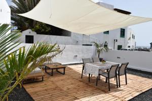 eine Terrasse mit einem Tisch, Stühlen und einem weißen Regenschirm in der Unterkunft Sabbia Suite Casa Jalofa in El Golfo