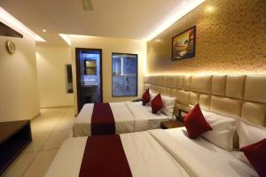 una camera d'albergo con due letti con cuscini rossi di Hotel Hindustan Residency Thane a Thane