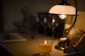 a candle in a glass next to a lamp on a table at Tenuta Montezeglio Country Family House in Invorio Inferiore