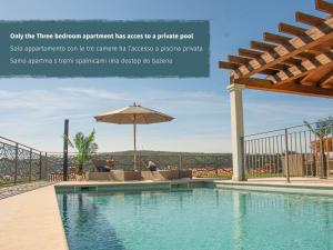 a swimming pool with a patio and an umbrella at Salinea Apartments in Sečovlje