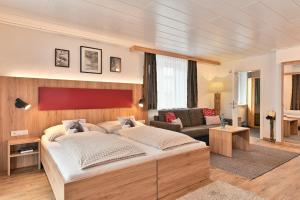 a bedroom with a large bed and a couch at Haus Flexen Appartements & Suite in Stuben am Arlberg