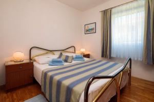 een slaapkamer met een bed met een blauw en wit gestreepte deken bij Apartment Oaza in Supetar
