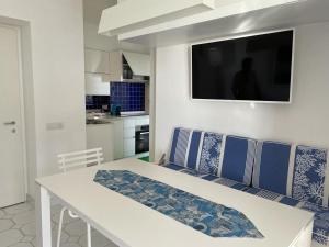 a living room with a table and a television on the wall at Le Rocce da Tragara, Tragara essential in Capri