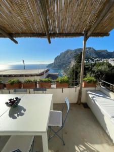 uma mesa e cadeiras numa varanda com vista para o oceano em Le Rocce da Tragara, Tragara essential em Capri