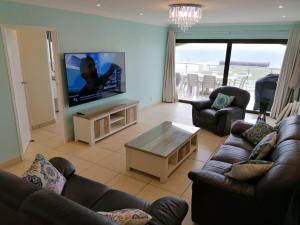 307 Bermudas - by Stay in Umhlanga في ديربان: غرفة معيشة مع كنب وتلفزيون بشاشة مسطحة
