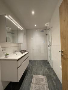 uma casa de banho branca com um lavatório e um chuveiro em Appartement Mona em Bürserberg