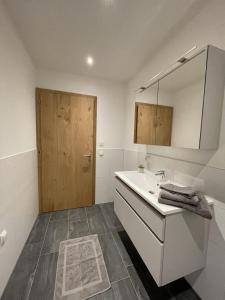 uma casa de banho com um lavatório e uma porta de madeira em Appartement Mona em Bürserberg