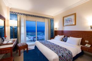 a hotel room with a bed and a large window at Swiss Wellness Dive Resort in Hurghada