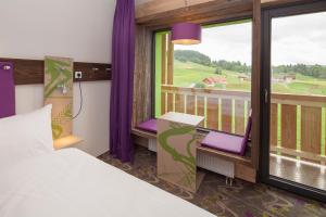 a bedroom with a bed and a balcony with a view at Explorer Hotel Neuschwanstein in Nesselwang +49 photos