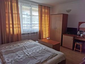 a bedroom with a bed and a desk and a window at Къща за гости Aтанасов II in Primorsko