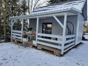 a tiny house with a porch in the snow at Domek na korcie in Lubomierz