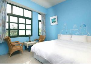una camera da letto con un letto grande e una parete blu di Wushih Surf Hostel a Toucheng