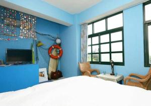 una camera blu con un letto e una TV di Wushih Surf Hostel a Toucheng