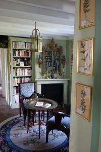 een woonkamer met een tafel en een open haard bij les chambres de la tour in Le Bec-Hellouin