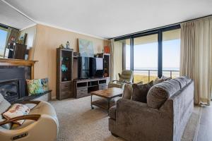 sala de estar con sofá y TV en Sand & Sea: Wave Watcher (302), en Seaside