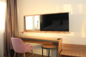 a room with a tv and a chair and a mirror at O&O Hotel Oberursel Zentrum in Oberursel