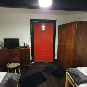 eine rote Tür in einem Zimmer mit einem Schreibtisch und einem TV in der Unterkunft Vila Brajčić in Radatovići