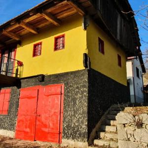 ein gelbes und rotes Haus mit einer roten Tür in der Unterkunft Vila Brajčić in Radatovići