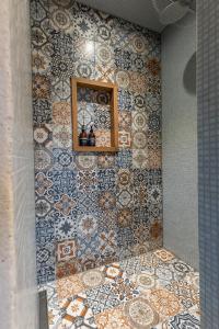 a bathroom with a tiled wall with a mirror at De oude slaght- luxe suite met buitensauna in Zaandam