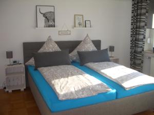 a bedroom with a blue bed with two pillows at Ferienwohnung RheinSpaziert in Dellhofen
