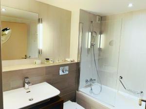 a bathroom with a shower and a sink and a toilet at Holiday Inn Paris Montmartre, an IHG Hotel in Paris