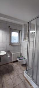 baño con aseo y lavabo y ventana en Pension und Ferienwohnung Walther, en Storkow