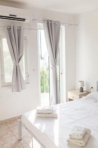 een witte slaapkamer met een wit bed en een raam bij CrossRhodes Villas in Pefki Rhodes