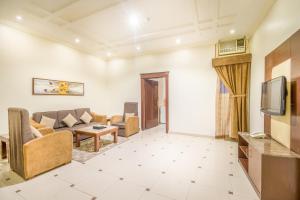 sala de estar con sofá y TV en Al Muhaidb Hotel Apartments 24, en Riad