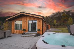 a small cabin with a hot tub in front of it at Balloch Park in Aberfeldy