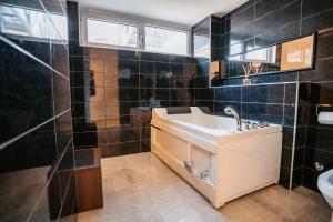 un bagno piastrellato nero con lavandino e specchio di MAGICO Rooms & Apartments a Niš