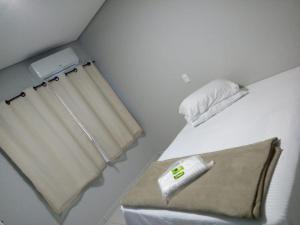 um quarto com uma cama com uma janela e uma toalha em Hotel Pousada Bueno's em Francisco Beltrão