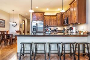 a kitchen with wooden cabinets and a counter with bar stools at Rolling Ridge 20C - Wildernest in Silverthorne