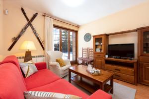 a living room with a red couch and a tv at Pie de pistas Fontcanaleta Lamolina in La Molina