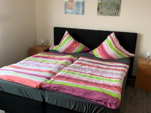 a bed with colorful blankets and pillows on it at Gästehaus Vogel in Horumersiel