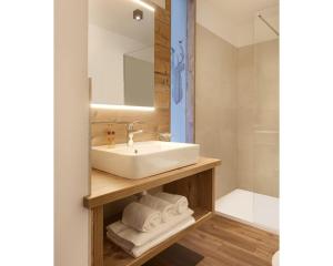 W łazience znajduje się umywalka, lustro i prysznic. w obiekcie Hotel Al Cervo w mieście Tesero