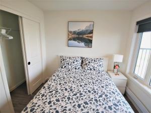 ein Schlafzimmer mit einem Bett mit einer Bettdecke in der Unterkunft Serene 2 bedroom condo with balcony and lakeview in Winnipeg