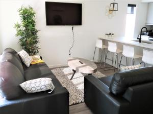 a living room with a black couch and a kitchen at Serene 2 bedroom condo with balcony and lakeview in Winnipeg