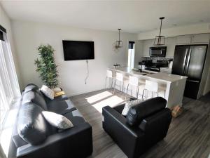 a living room with two black couches and a kitchen at Serene 2 bedroom condo with balcony and lakeview in Winnipeg