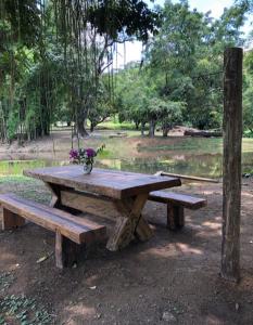 einen hölzernen Picknicktisch mit einer Vase Blumen darauf in der Unterkunft Vivenda dos Guaranys: casa + loft in Conservatória