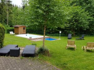 a backyard with a swimming pool and chairs and a tree at Verwöhn-Pension Wiesengrund in Bischofsgrün
