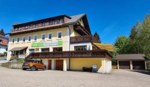 un bâtiment avec une voiture garée devant lui dans l'établissement Verwöhn-Pension Wiesengrund, à Bischofsgrün