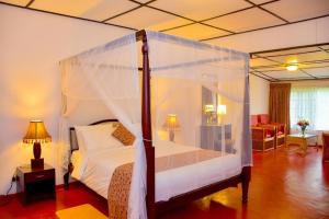 ein Schlafzimmer mit einem Himmelbett in der Unterkunft BloomsDale Country House in Haputale