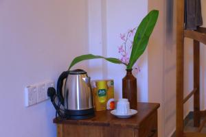 a table with a coffee maker and a vase with a plant at Monkey Beach in Dickwella